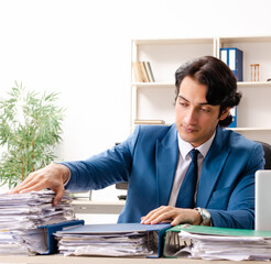 Young handsome busy employee sitting in office
