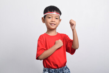 Happy Asian boy in red t-shirt raising his hand in air with happy and successful expression, isolated on white background. Indonesian Independence Day concept.