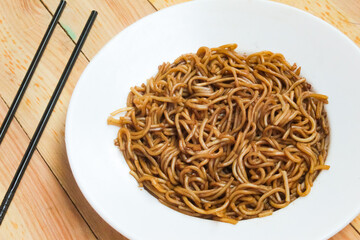 a plate of ramen noodles with chopsticks on a wooden table