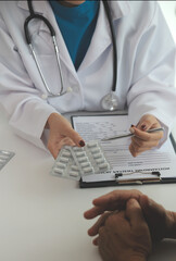 Doctor prescribing medicine giving pills to senior grandmother patient at hospital.