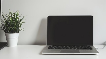 A laptop computer with a blank screen sits on a white desk.