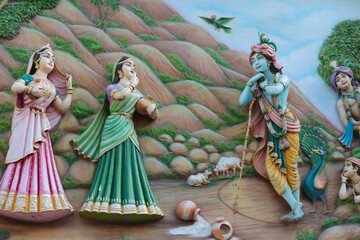 Krishna the cowherd and gopis - bas-relief on the wall of a Hindu temple in India.