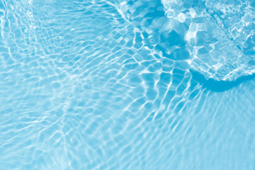 Blue water with ripples on the surface. Defocus blurred transparent blue colored clear calm water surface texture with splashes and bubbles. Water waves with shining pattern texture background.