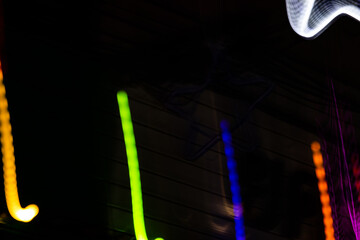 Obraz premium A series of neon lights are displayed in a black background. The lights are in various colors, including green, yellow, and purple. Scene is energetic and vibrant