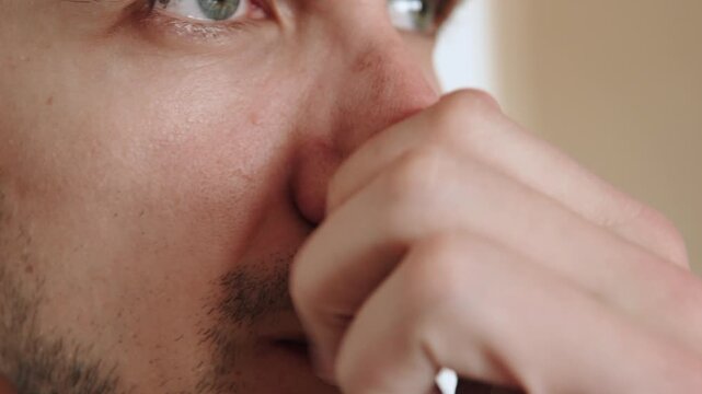 Caucasian man massaging and scratching his nose with his hand close up. Exposure to irritant and elimination of itching from sneezing. Manifestations and symptoms of allergies in person.