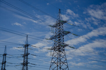 High Voltage Transmission Lines Poles Against Blue Sky Background