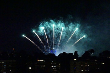 Fireworks illuminate night sky over silhouetted cityscape in Madrid, Spain