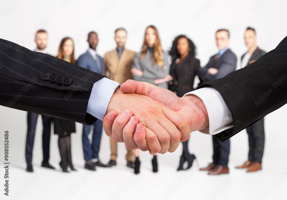 Aufkleber two people shaking hands in focus with a diverse group of professionals standing in the background, 