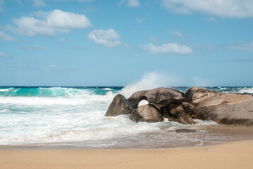 Waves from the Mediterranean sea crash onto rocks and the sandy beach at Aregno Plage near Algajola in Corsica