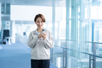 携帯を持つ作業着を着たショートヘアーの女性