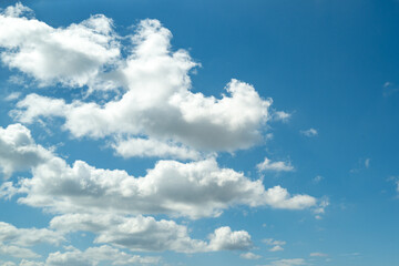 Sun shining through the puffy clouds. White clouds banner. Beautiful clouds. Background with clouds on blue sky. Summer Cloud on blue sky.
