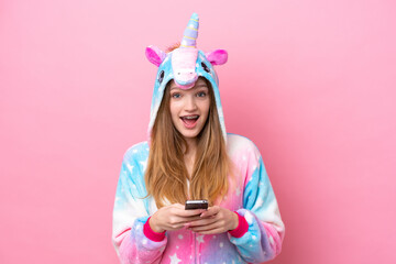 Teenager Russian girl with unicorn pajamas isolated on pink background surprised and sending a message