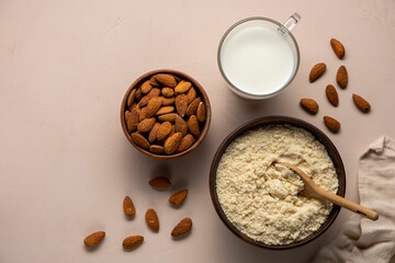 Almond milk in glass, flour in wooden brown spoon and nut kernels. Vegan or keto diet concept.