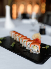 Delicious Philadelphia with juicy salmon and fresh cucumber, along with creamy Philadelphia cheese, on a beautiful white tablecloth in a cozy and nice restaurant