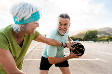 Beautiful happy senior couple playing basketball and having fun - Mature married couple in love...