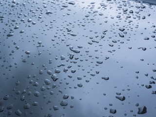 Raindrops on black car close up for rainy season travel background.        