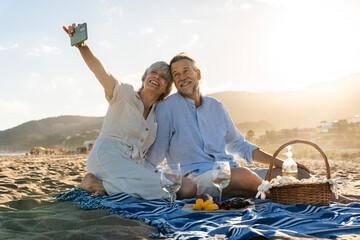 Beautiful happy senior couple dating at the seaside during summertime - Mature married couple in...