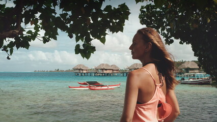 Happy tourist woman relax on Bora Bora island. Young female enjoy water villa bungalows sea view....