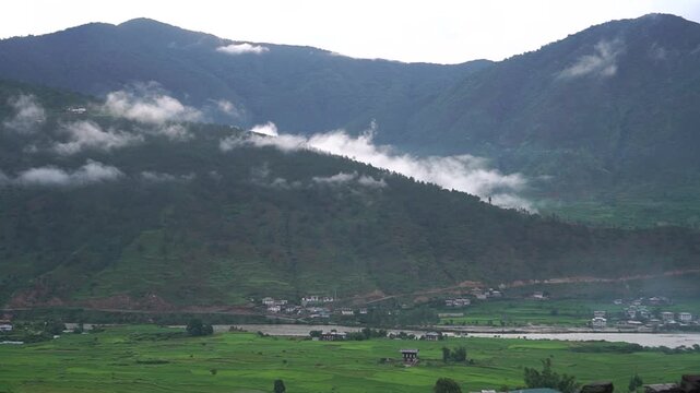 Time-lapse View Punakha rice terraces in punakha landscape with mountain hill fog clouds look at Bhutanese traditional village and river flowing through. Destination place that everyone must travel
