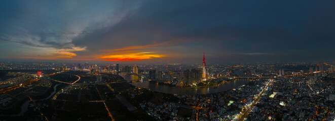 An aerial view of Ho Chi Minh City at sunset, vibrant colorful sky, the illuminated Landmark 81 skyscraper, the reflecting Saigon River in city lights of dynamic urban, awe cityscape