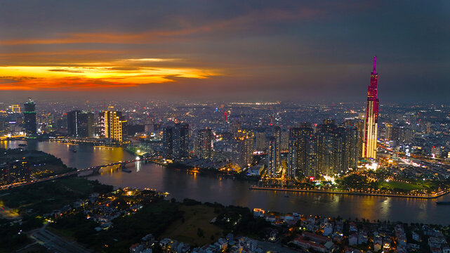 An aerial view of Ho Chi Minh City at sunset, vibrant colorful sky, the illuminated Landmark 81 skyscraper, the reflecting Saigon River in city lights of dynamic urban, awe cityscape
