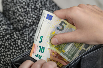 Młoda dziewczyna wymienia pieniądze na euro i chowa banknoty do portmonetki, 
