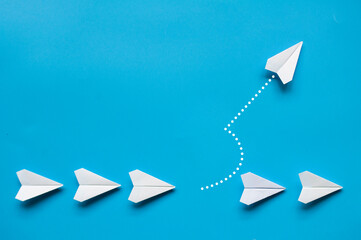 White paper airplane leaving the rest of the airplanes. Customizable space for text.