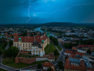 The Royal Castle on Wawel Hill during a storm during the day. In the background, lightning strikes the ground. Krakow, Poland, Europe