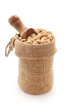 Close-up of Organic Soya Chunks (Glycine max), in a jute bag with a scoop, Isolated on a white background.