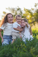 Obraz premium Three cheerful and happy children brouther and sisters are enjoying a playful and delightful moment in a sunlit grass field full of joy.