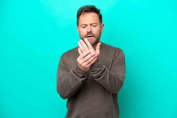 Middle age caucasian man isolated on blue background suffering from pain in hands