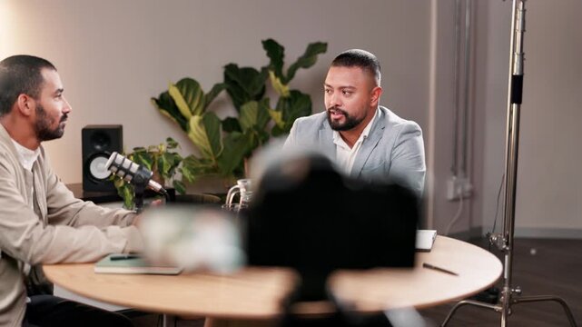 Conversation, microphone and podcast with influencer men in recording studio for live radio broadcast. Interview, media or news with guest and talk show host streaming subscription content on air