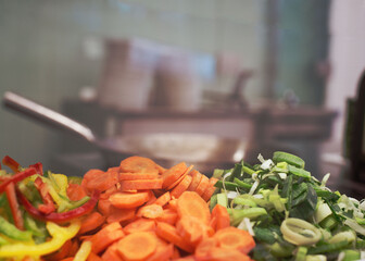 geschnittene Paprika, Karotten und Lauch vor Hintergrund Wok und K&uuml;che