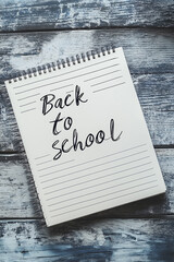 Notebook with the inscription back to school lying on a rustic wooden desk