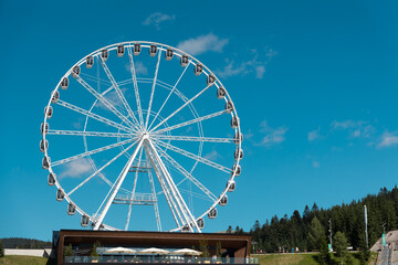 Ferris Wheel on Sunny Day. A Ferris wheel stands prominently against a clear blue sky on a sunny...