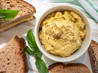 Avocado cashew homemade spread for sandwiches on white wooden board