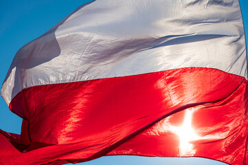 Powiewająca flaga biało czerwona. Flaga Polski na tle niebieskiego nieba © smoku7979