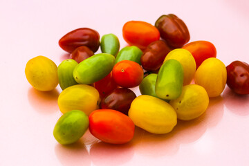 Cocktail tomatoes in different colors, red, orange, green, yellow on pastel background