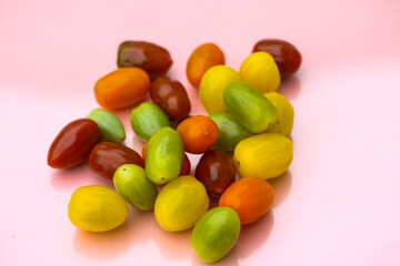 Cocktail tomatoes in different colors, red, orange, green, yellow on pastel background
