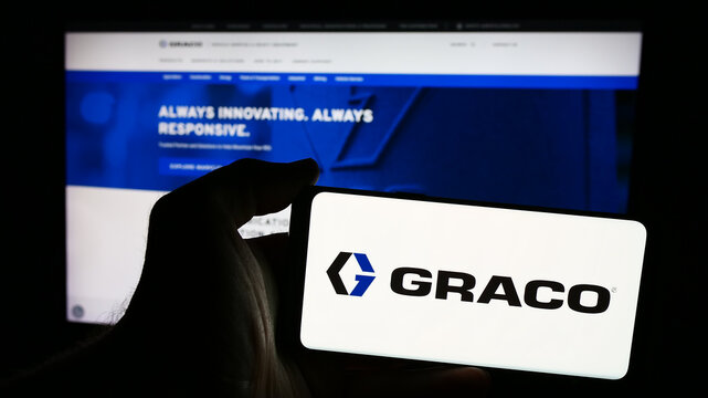 Stuttgart, Germany - 07-24-2024: Person holding smartphone with logo of US fluid-handling equipment company Graco Inc. in front of website. Focus on phone display.
