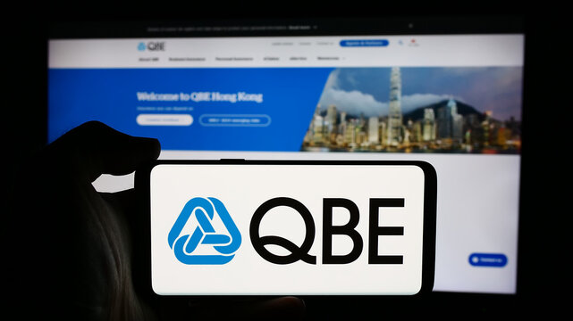 Stuttgart, Germany - 07-25-2024: Person holding cellphone with logo of Australian company QBE Insurance Group Limited in front of business webpage. Focus on phone display.