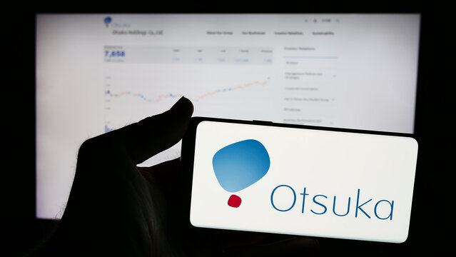 Stuttgart, Germany - 07-29-2024: Person holding mobile phone with logo of Japanese company Otsuka Pharmaceutical Co. Ltd. in front of business web page. Focus on phone display.