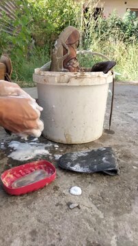Time lapse washing beige winter leather boots made of natural nubuck with solid laundry soap and water from a plastic bucket, removing shoelaces, insoles. Hand work