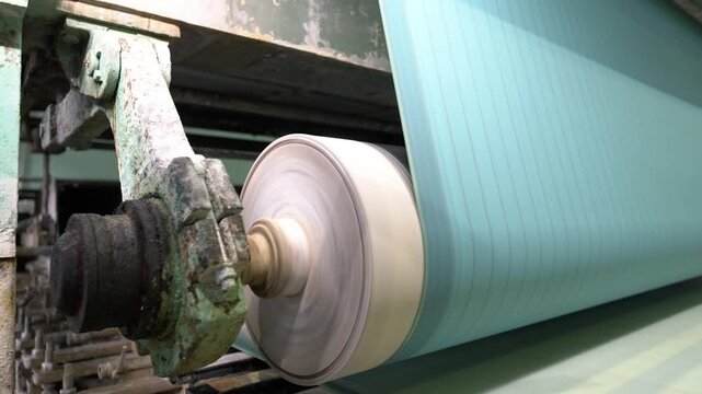 Transmission shaft rotates on conveyor belt at production plant closeup. Turning roller of transporting line at papermaking factory
