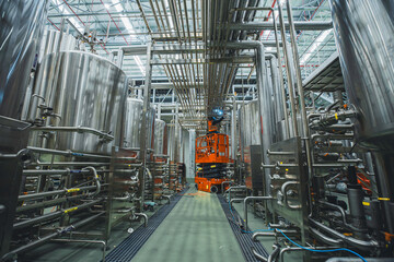 Workers working on the construction site of the new factory industry for boom lift process pipeline stainless steel tanks