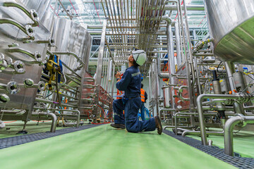 Fototapeta premium Male work visual draft inspection process stainless steel tanks and in equipment tank facility for beer drinks cellar at the with vertical stainless