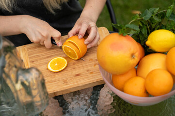 female hands cutting fruit for lemonade in the garden