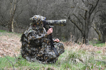 Photographer in camouflage in the forest
