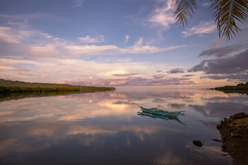 Seascape bay view with fisher boat outrigger in sunset 