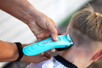 A hairdresser cutting the hair of a blond boy. Close-up shots.